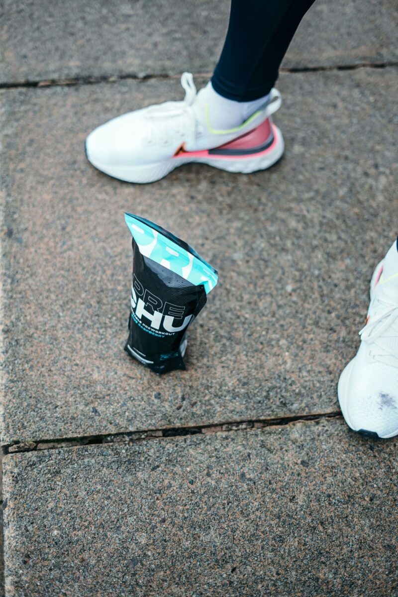 Proteinpulver auf Straße mit Läuferin – Symbol für Sporternährung